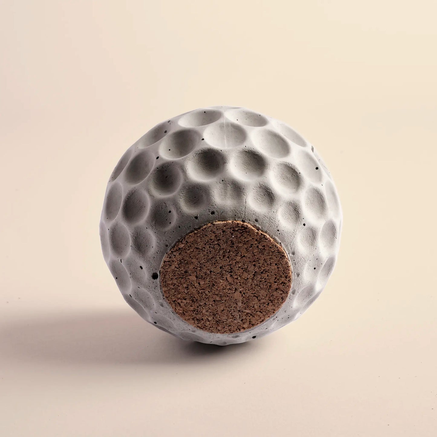 Small plant pot handmade from concrete. It is round with decorative circular dents. The image shows the bottom of the pot.