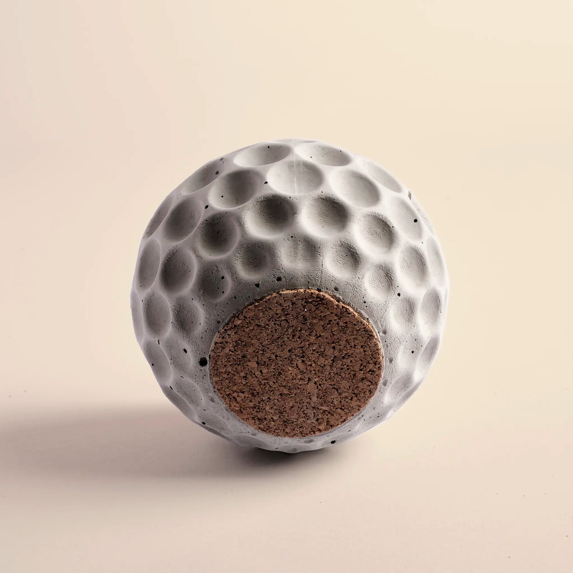 Small plant pot handmade from concrete. It is round with decorative circular dents. The image shows the bottom of the pot.