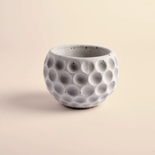 Small plant pot handmade from concrete. It is round with decorative circular dents.