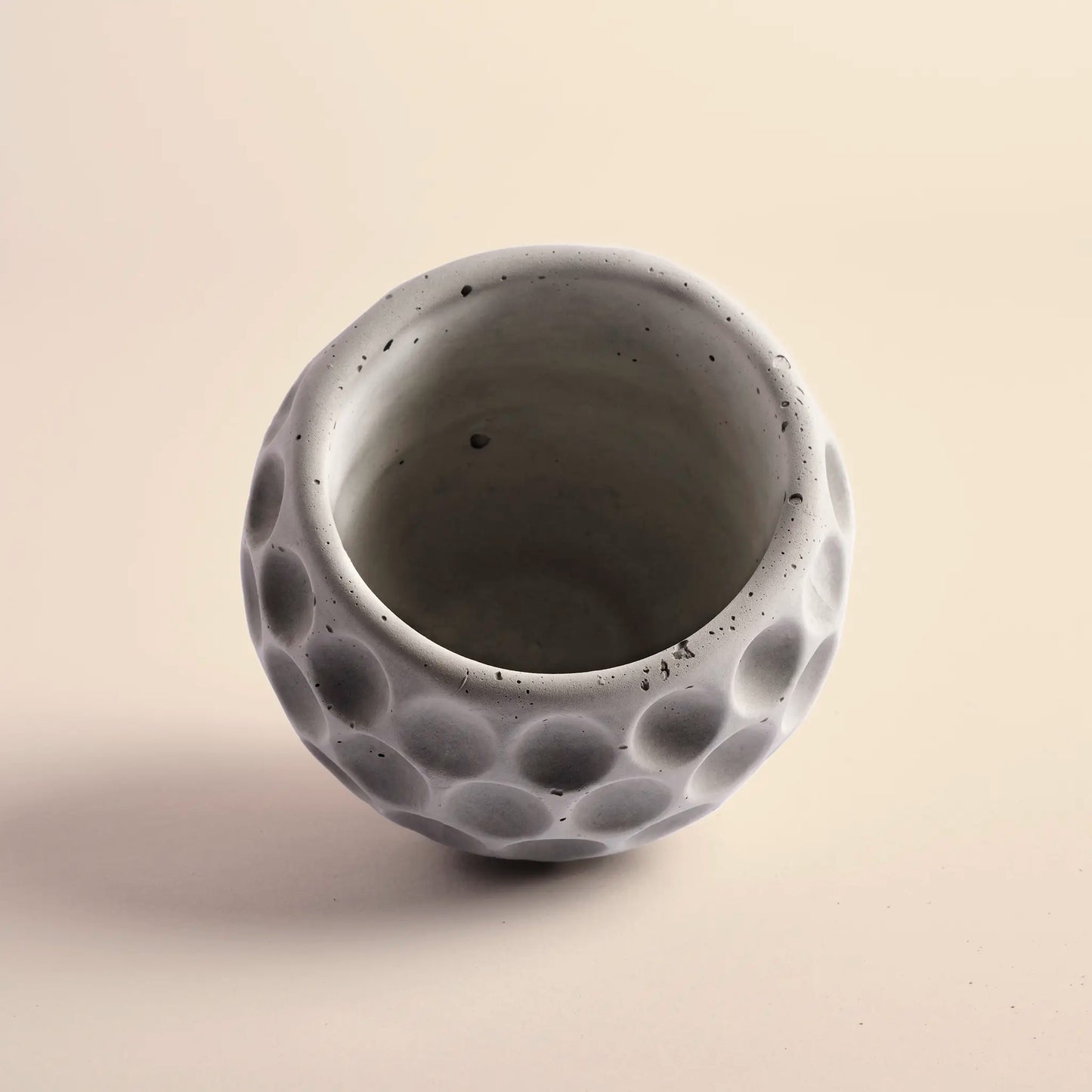 Small plant pot handmade from concrete. It is round with decorative circular dents.