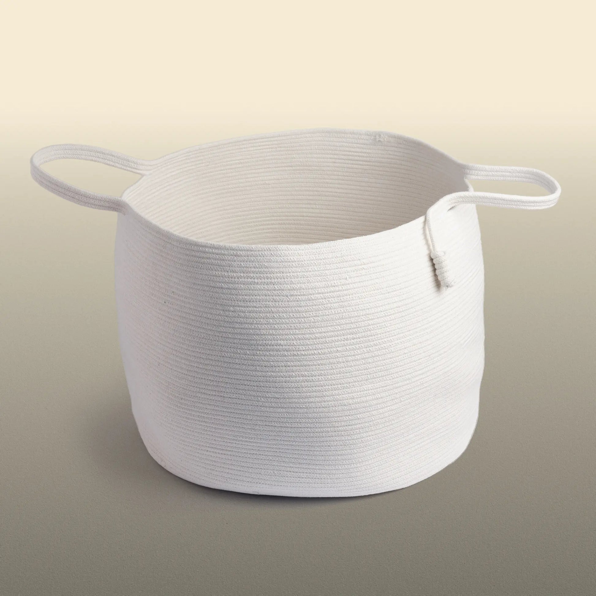 Homeware basket handmade from white cotton. The basket is round and has two handles. 