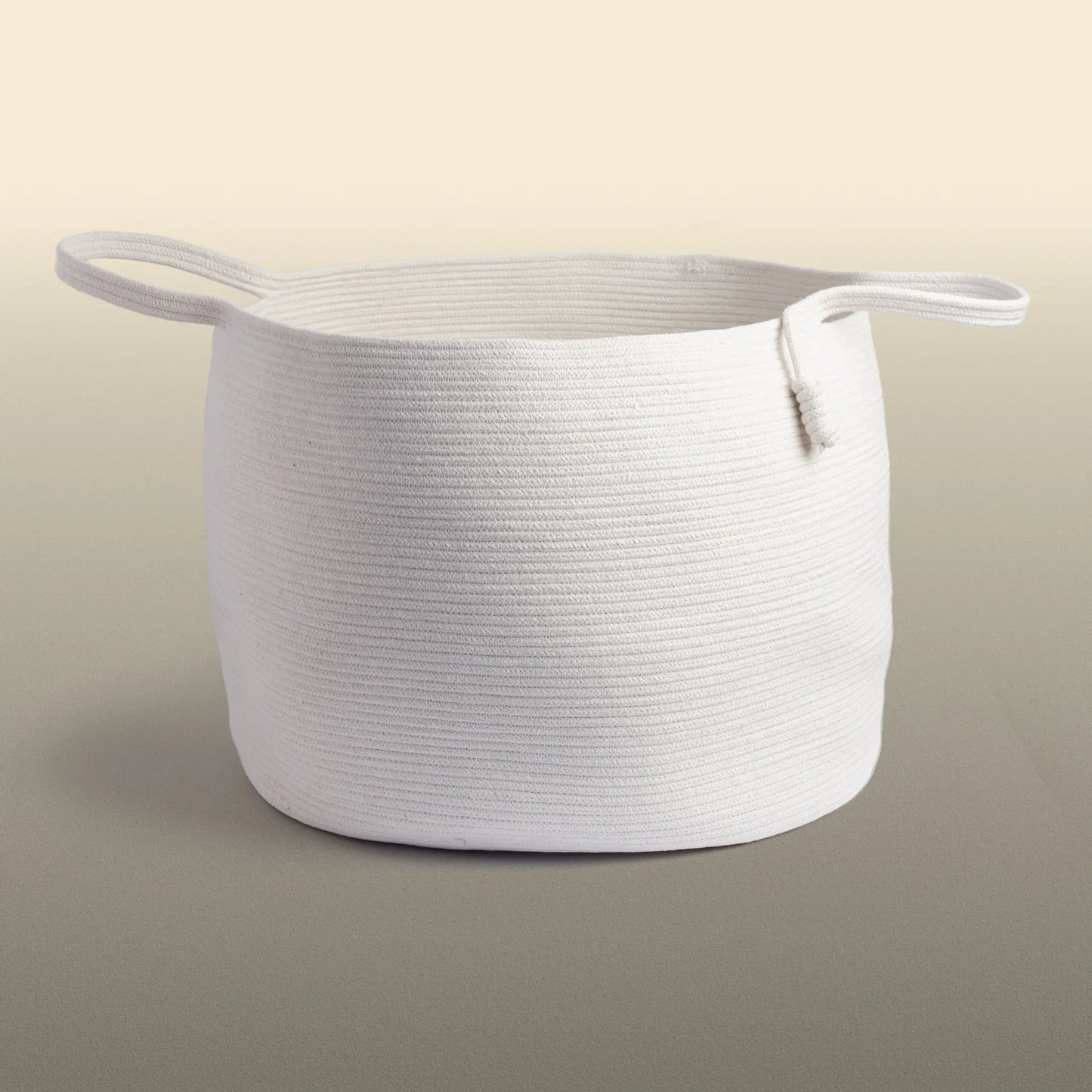 Homeware basket handmade from white cotton. The basket is round and has two handles. 